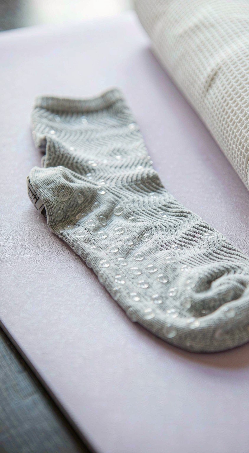 Close-up of the silicone grip dots on the sole of a non-slip plus size grip sock on a yoga mat
