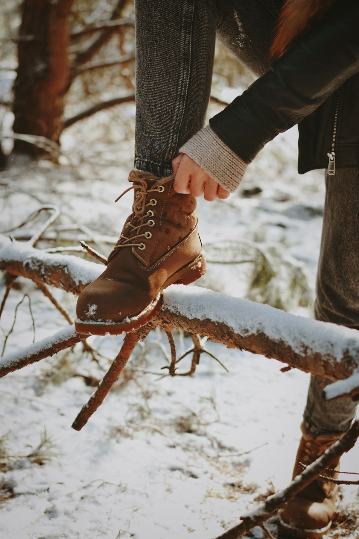 Woman lacing a winter boot in the snow while wearing plus size ski socks