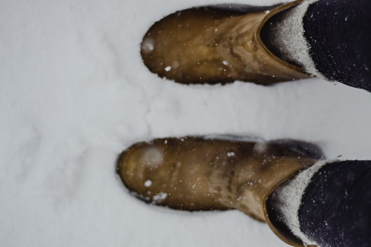 Plus size ski socks inside brown snow boots on a snowy winter trail outdoors