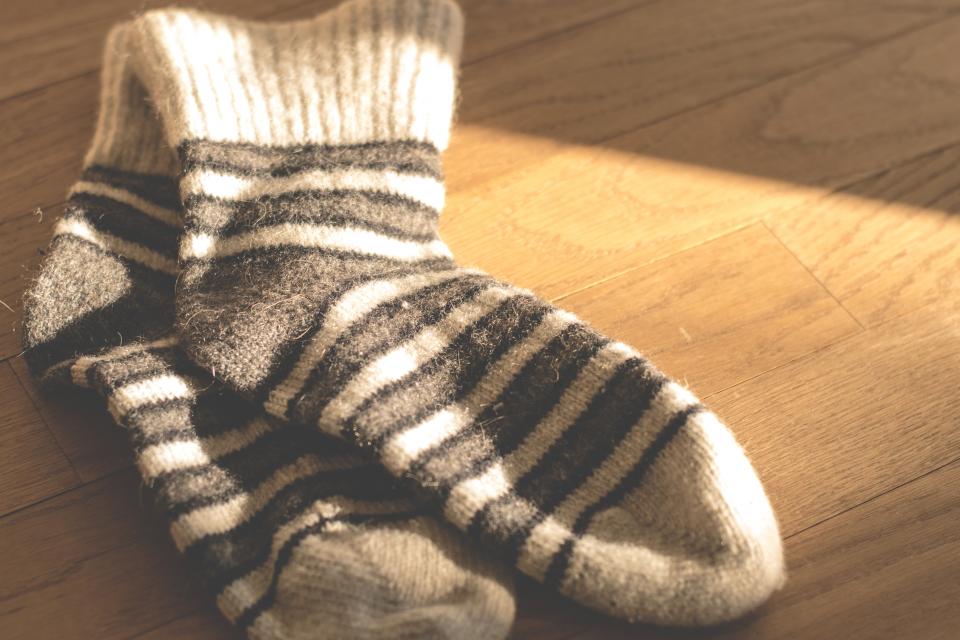 Thick plus size thermal socks in wool stripes resting in warm sunlight on a floor