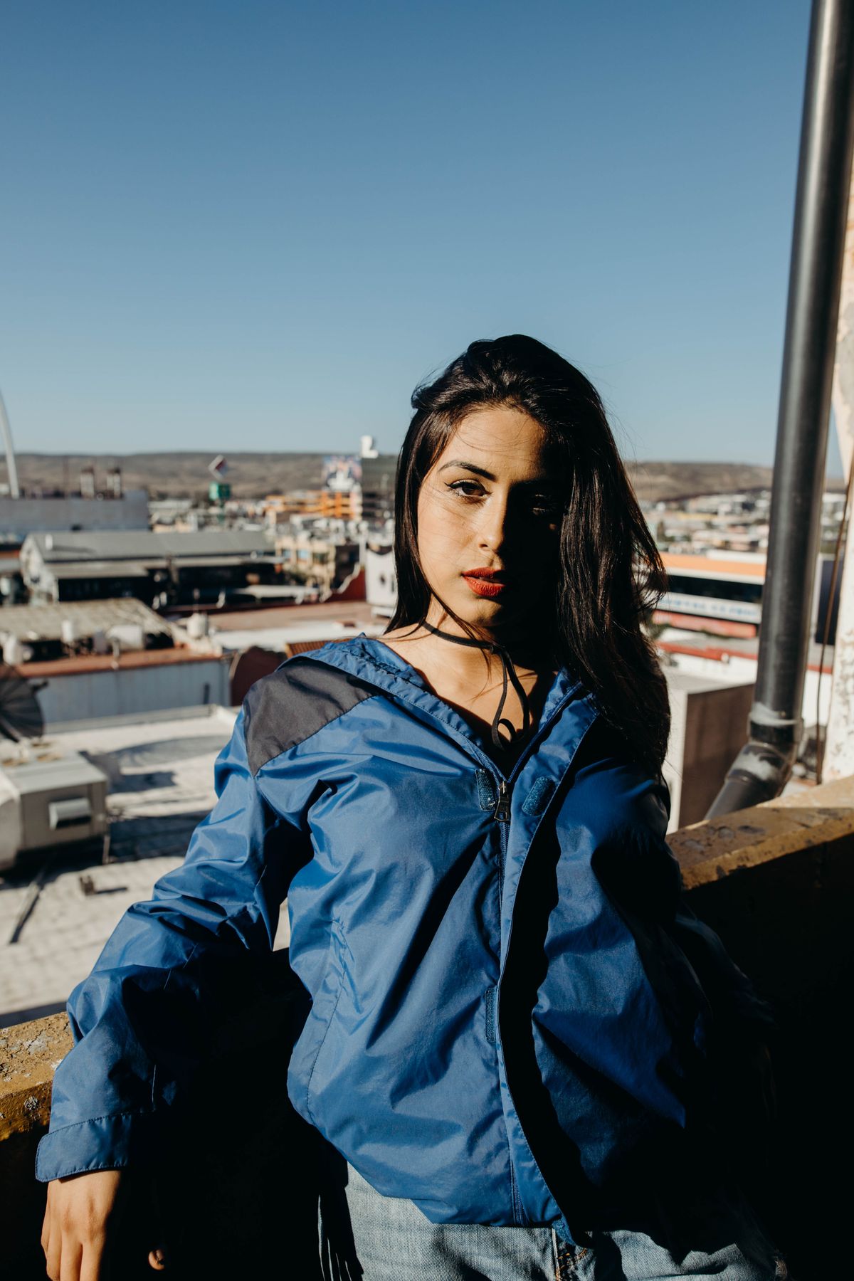 Plus size windbreaker jacket in blue worn outdoors on a sunny city rooftop
